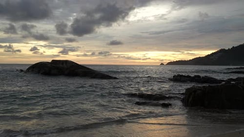 The beginning of a beautiful sunset on the beach. Waves and large stones. Phuket