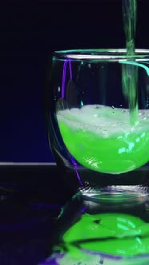 Close Up of Pouring Green Cocktail Beverage in a Transparent Glass Standing on Bar Counter Stock