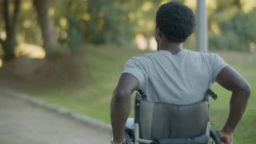 Young Black Man Riding His Wheelchair in Park on Summer Day