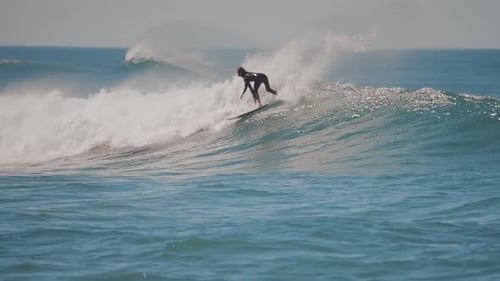 Amazing slowmotion shot of a male surfer riding the perfect ocean wave