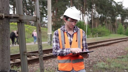 A civil engineer takes measurements of a metal structure. Critical rail infrastructure.