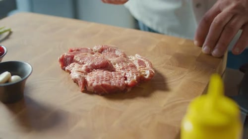 Hand of Cook Beats Off a Delicious Juicy Piece of Pork Meat with Kitchen Hammer