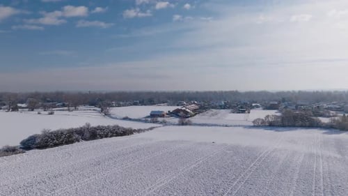 Aerial video capturing a picturesque winter landscape with snow-covered fields, scattered trees, and