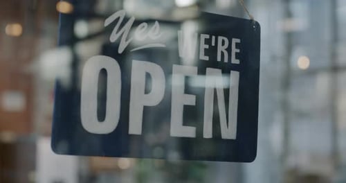Closeup of Yes We are Open Sign on Transparent Glass Shop Door Inviting Customers in Morning