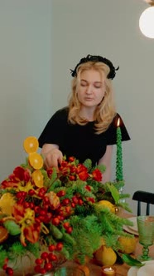 Woman Arranging Festive Centerpiece at Home on Table