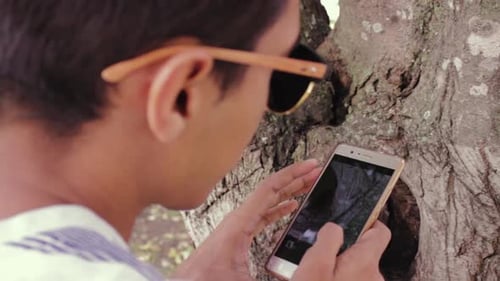 young man using his cell phone to take photos of nature.