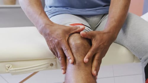 Midsection of african american man touching his leg at hospital