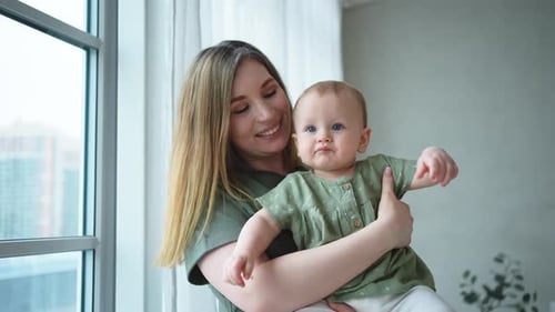 Mother Holding Baby in Front of Window
