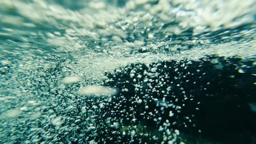 Slow motion of air bubbles floating from river bottom to the water surface. Air bubbles in the blue
