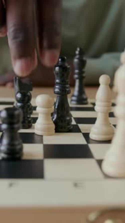 Person Moves Chess Pieces on Game Board