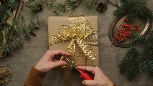 Hands Trimming a Bow on Christmas Gift