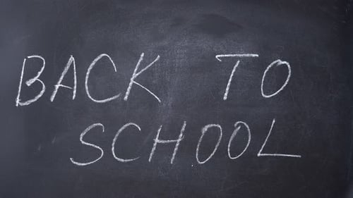 Back to school chalk text appears on a school black board.