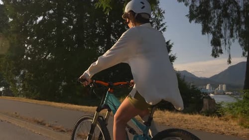 Biker In Helmet Riding Bicycle In The Park During Sunset. - close up shot