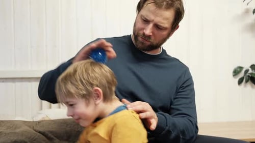 Father Using a Spiky Massage Ball for Son to Relieve Muscle Tension Aid Recovery After Intense