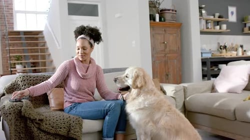 Woman Cuddling Golden Retriever on Couch at Home