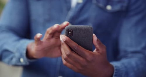 An unrecognizable man using his cellphone while out in the city