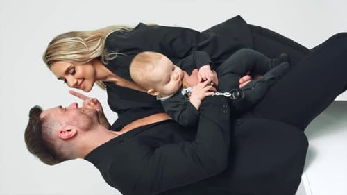 Husband and wife in black suits kissing. Happy couple with lovely baby boy in studio.