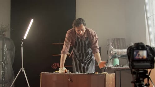 Un reparador de muebles en un taller de trabajo mantiene un tutorial en línea sobre la reparación de antigüedades