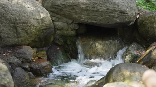 Water flows vigorously from a hole in a rock.