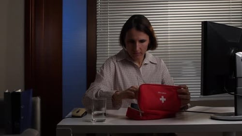 Woman at Desk Takes Pills from First Aid Kit