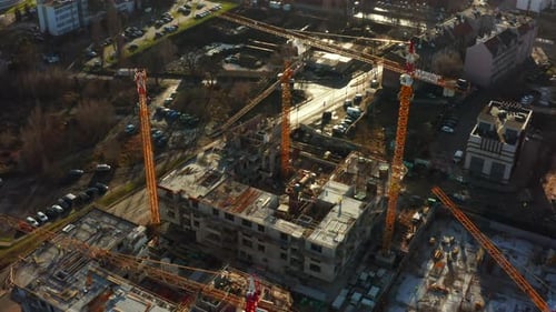 Hochbau mit Turmdrehkranen bei Sonnenuntergang