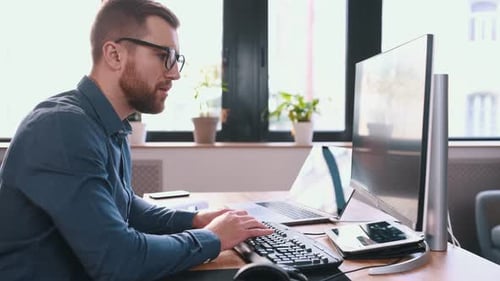 Programmer is working in the modern office. Sitting by computer