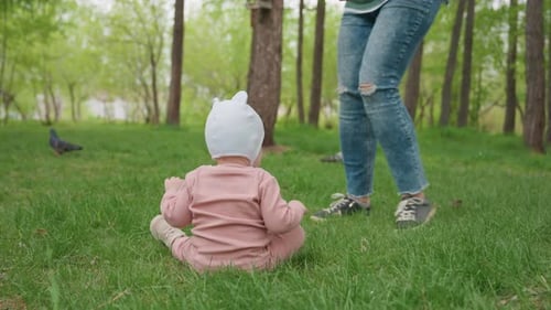 Infant Learns to Walk with Woman in Park