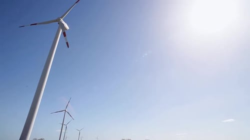 Tall wind turbines spinning against a clear blue sky on a sunny day