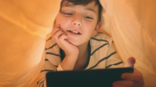 Boy Under Blanket with Tablet at Night