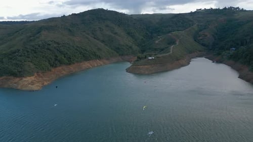 Aerial Lake Calima at Sunset with Kiteboarders at Distance. Pull Back Shot. Valle del Cauca. Colombi