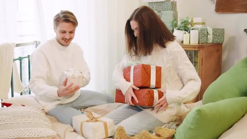 Young Couple Exchanging Christmas Gifts on Bed