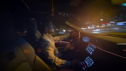 Man Driving Car Through City Streets at Night