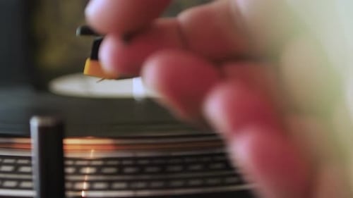 Close up of the stylus getting put onto the record. Men start playing vinyl record. Put the needle o