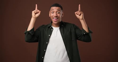 Un jeune homme afro-américain des années 20 porte une chemise en jean, pointe l'index, les doigts vers le haut sur quelque chose, geste isolé