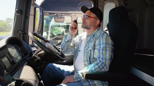 Truck Driver Communicates on Walkie-Talkie in Truck Cab