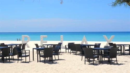 Tropisches Strandrestaurant mit RELAX-Schild auf weißem Sand