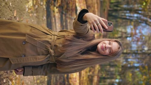 Young Female Blogger Standing in Park Taking Selfie Video