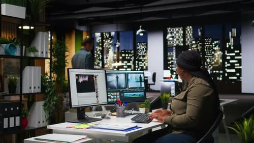 African American Female Editor Working with Dual Monitors in Creative Office