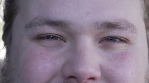 Macro eyes of a caucasian male person eyes squinting close up looking at camera