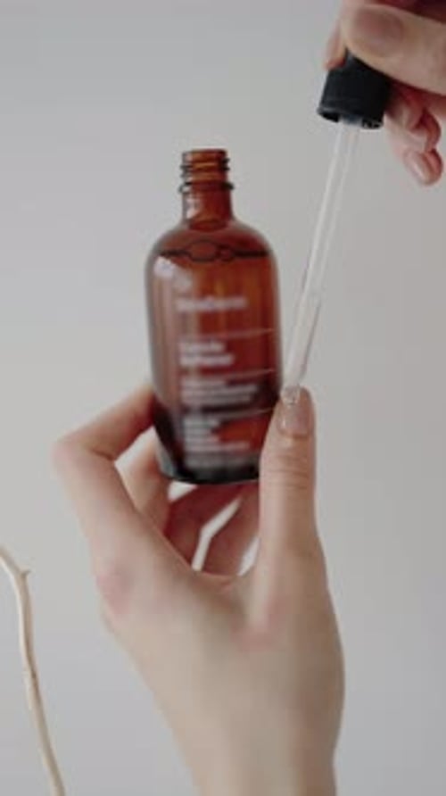 Hand Adds Liquid to Bottle with Pipette