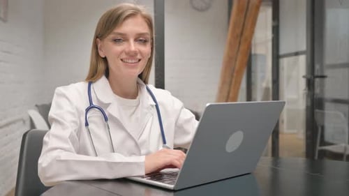 Female Doctor Using Laptop in Bright Office Setting