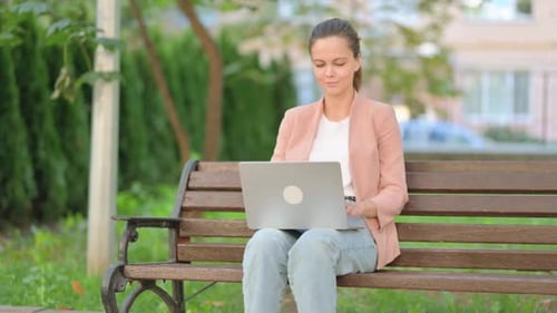 Woman Working on Laptop Computer Sitting on Bench
