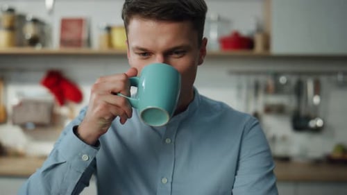 Freelancer trinkt Kaffee und arbeitet am Laptop in der Küche