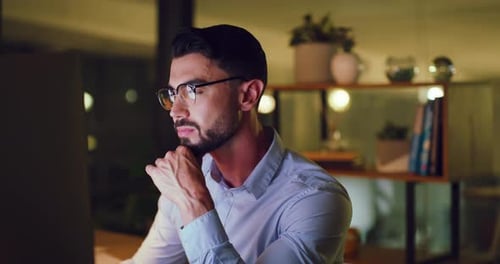 Young business man working overtime and browsing on a desktop computer while working late