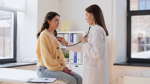 Doctor Listening to Patient's Heart with Stethoscope in Office
