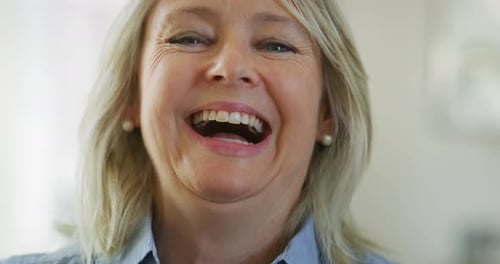 Authentic close up of an attractive mature blond hair woman with blue eyes is smiling in camera in