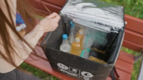 Una clienta recoge la comida pedida en una bolsa de entrega aislante al aire libre, mujer vestida de manera informal