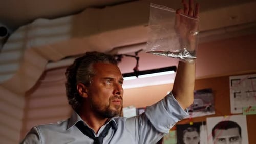 Closeup Detective's Office Middleaged Investigator in Shirt and Tie Sitting Desk Examining Evidence