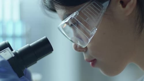 Woman Looking Through Microscope in Lab Close Up