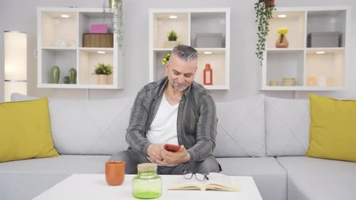 Old man laughing at phone message.